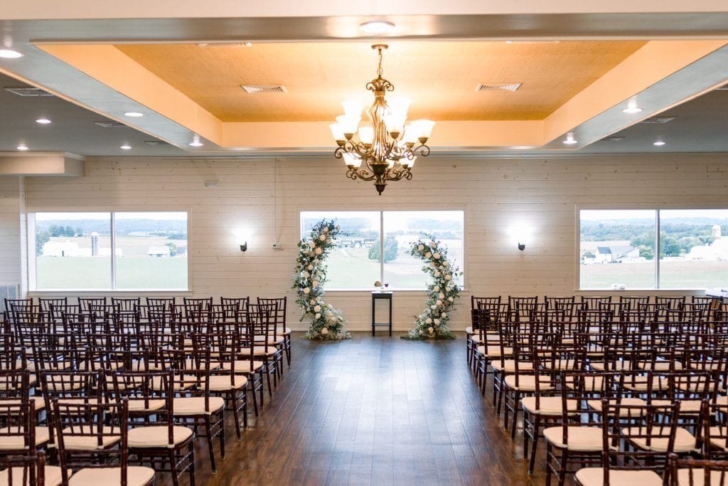 A spacious hall with rows of wooden chairs and a chandelier.