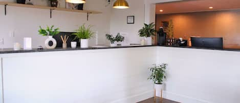 A modern kitchen with white cabinetry, a wooden countertop, and multiple pendant lights.
