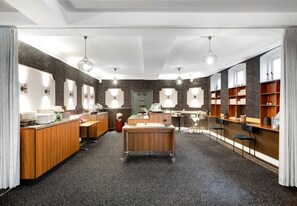 A modern bathroom with a central sink, vanity mirrors, and shelves with toiletries. - Hotel Ringkjøbing (Ringkobing)