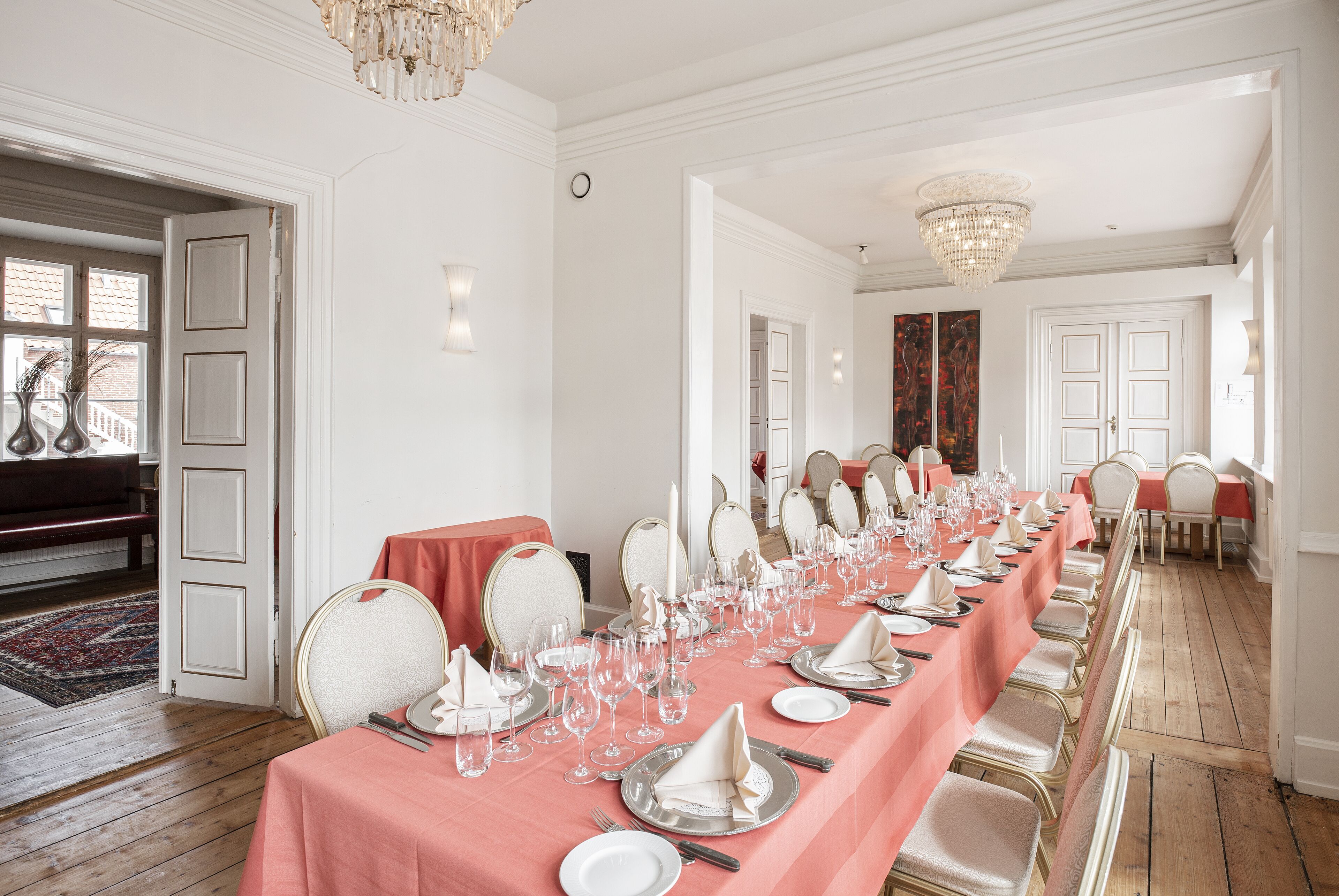 Une longue table à manger, dressée pour un événement formel, avec des chaises, de la verrerie et une décoration de table soignée.