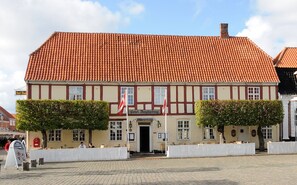 A traditional half-timbered building with a red-tiled roof, a sign reading "Hotel Kingjobing," and two flagpoles. - Hotel Ringkjøbing (Ringkobing)
