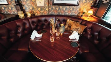 A round table with a dark wood finish, surrounded by a leather sofa with a tufted design.