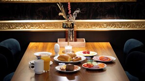 A breakfast table with various dishes, a coffee pot, and a vase with flowers. - Hotel Ringkjøbing (Ringkobing)