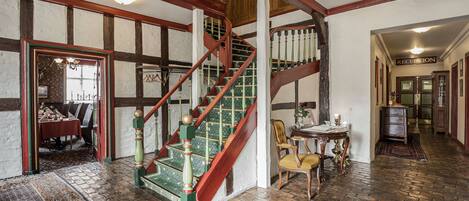 A staircase with a green and red color scheme, a reception area, and a dining area with a table set for two.