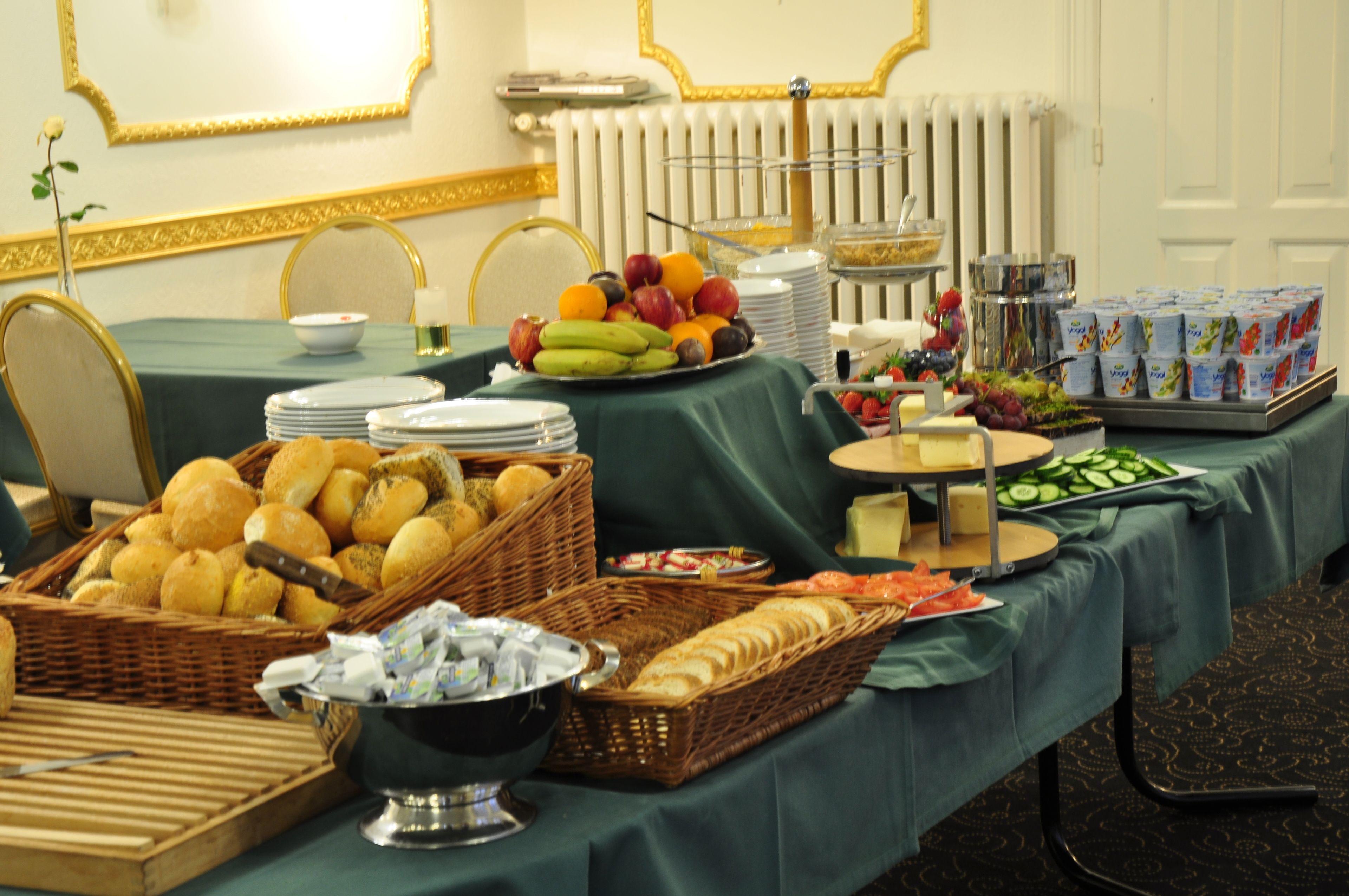 Una mesa de buffet con diversas opciones de comida y bebidas, entre ellas frutas, pan y productos lácteos.