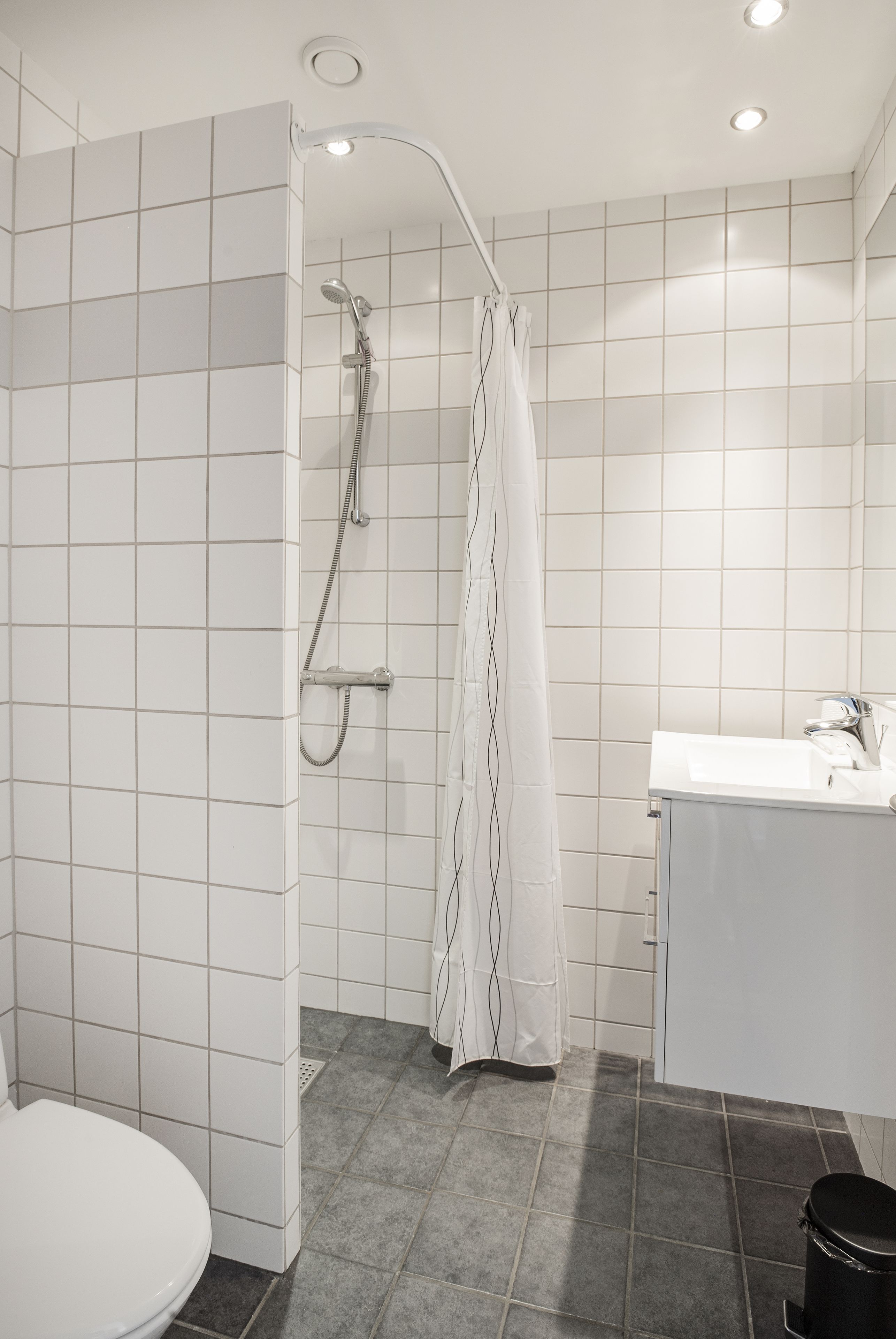 A bathroom with a shower, toilet, and sink.