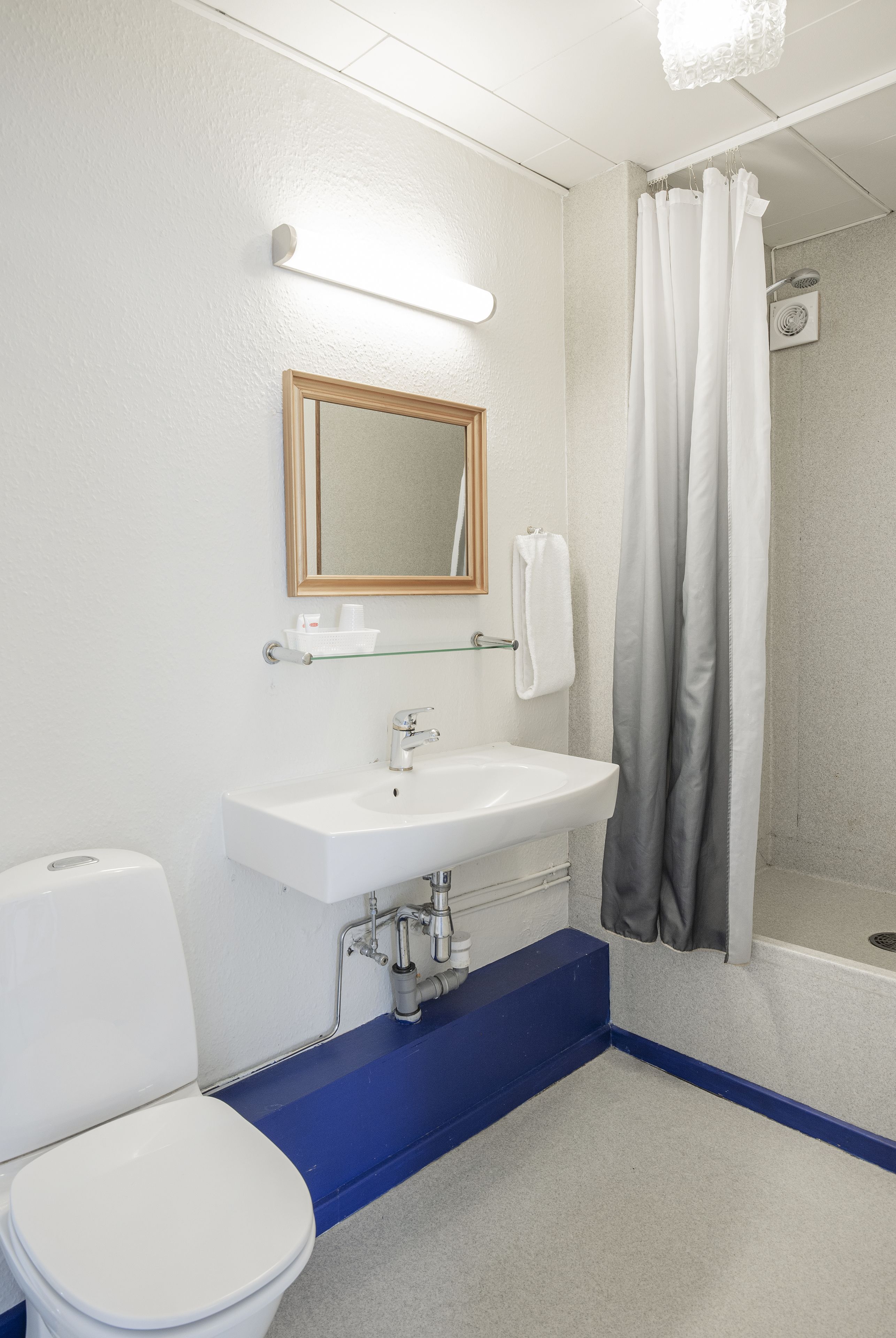 Een badkamer met een witte wasbak, een spiegel, een toilet en een douchegordijn.