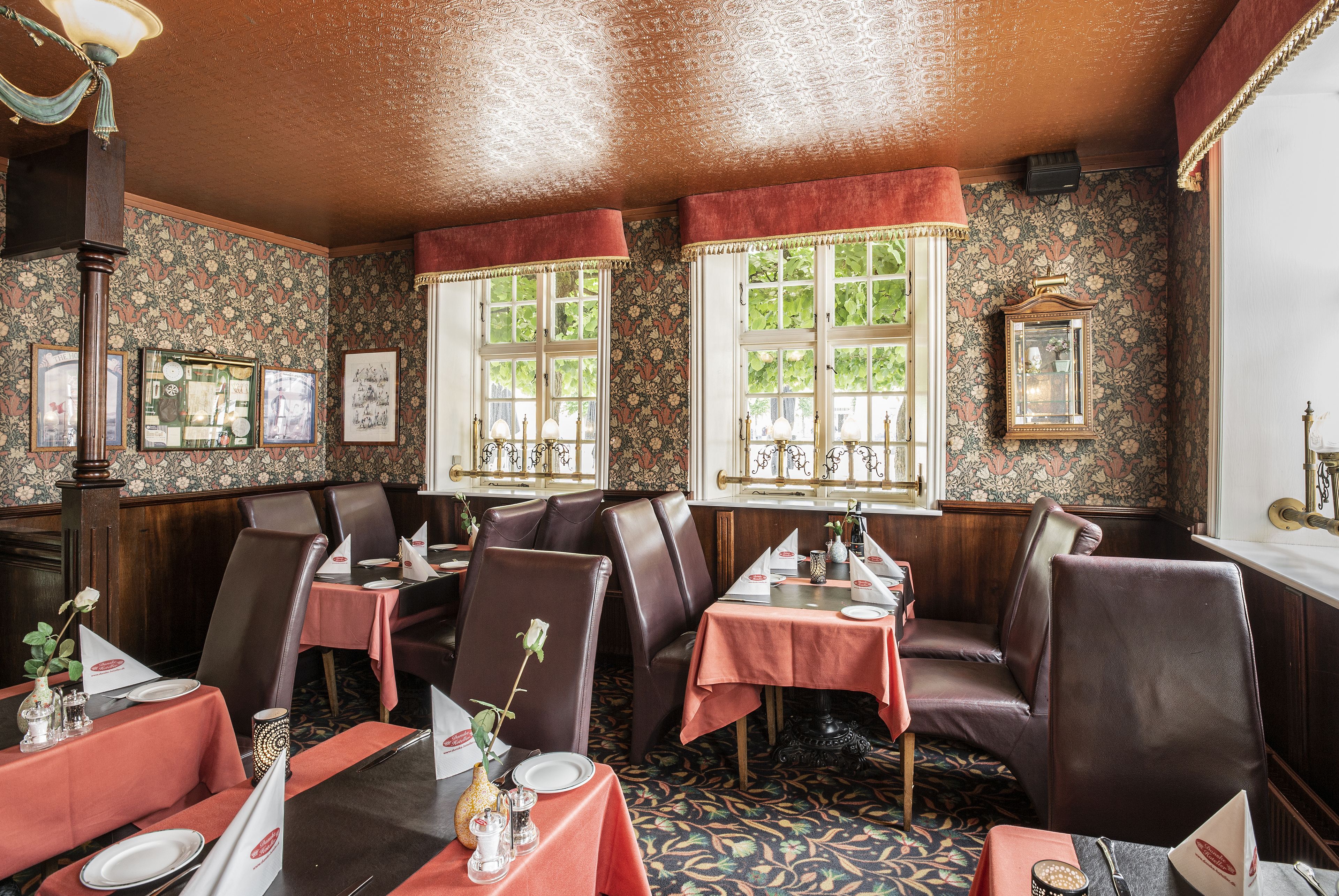 A dining area with tables set for service, chairs, and a patterned carpet.