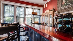 A bar area with a wooden counter, seating, and a wine rack. - Riverdale Inn (Jacksonville)