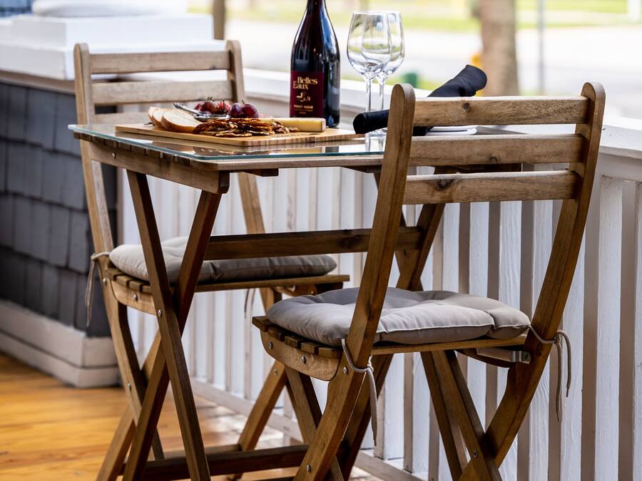 Et træspisebord med stole, en vinflaske og et glas på bordet.