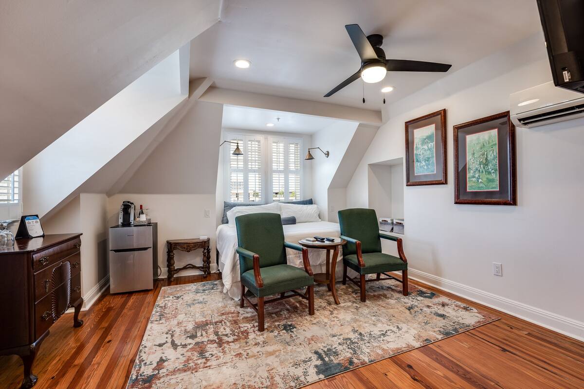 A bedroom with a sloped ceiling, a bed, a desk, and a chair.