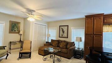 A living room with a sofa, armchair, coffee table, and a dining area with a table and chairs.