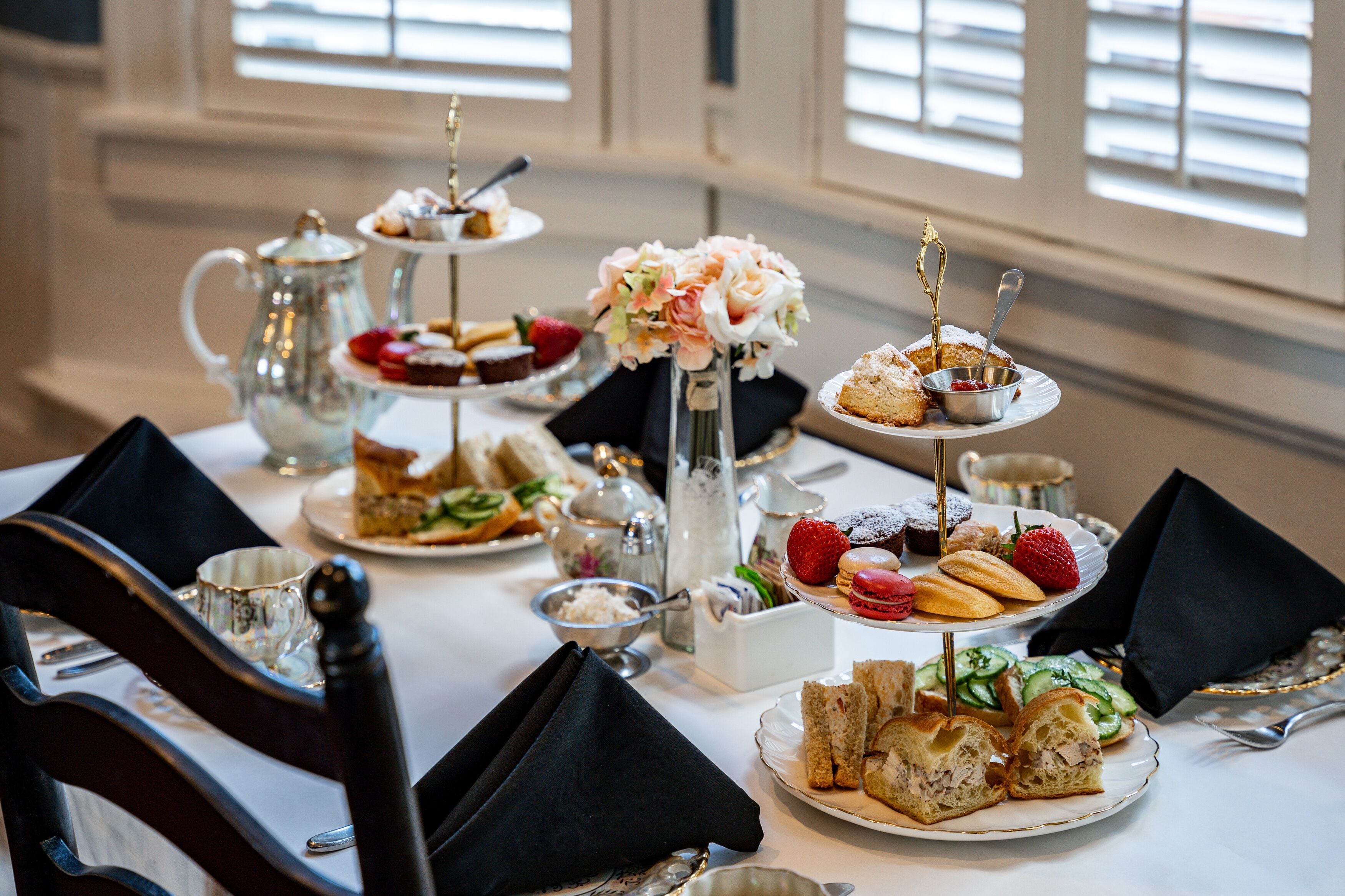 A table set for a tea service with various pastries and sandwiches.