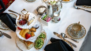 A table set for a tea service with multiple tiers of tea cups, saucers, and a variety of pastries and sandwiches. - Riverdale Inn (Jacksonville)