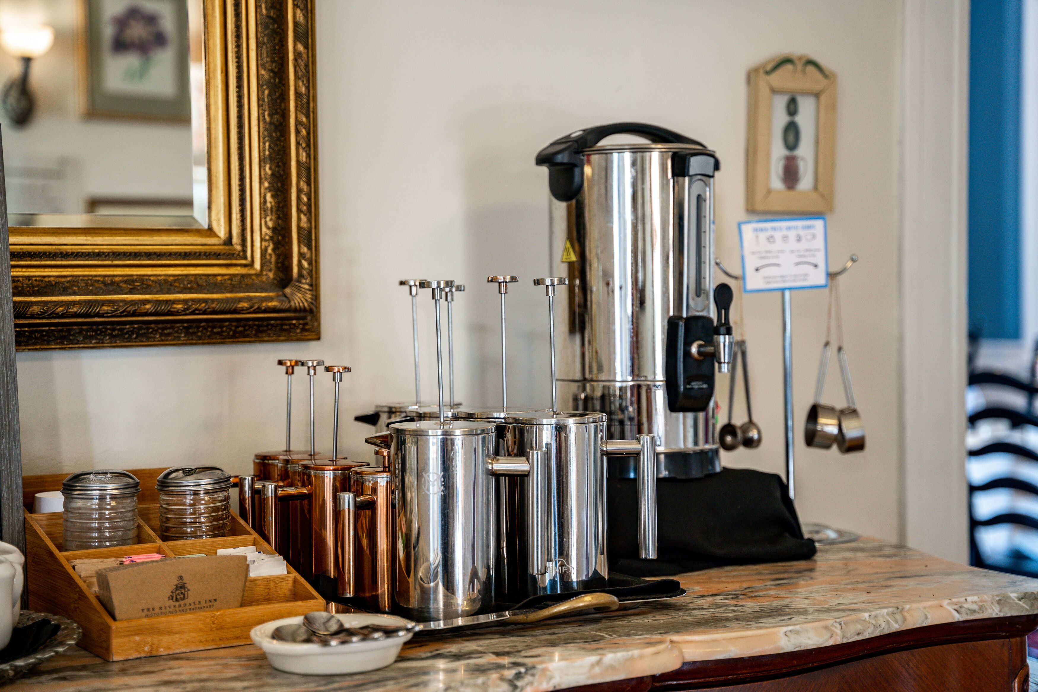 Una estación de café con una máquina de café, varios dispensadores de café y una bandeja con tazas.