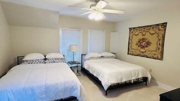 A bedroom with two beds, a ceiling fan, and a large tapestry on the wall.