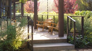 A wooden deck with a pergola, surrounded by lush greenery and a garden.