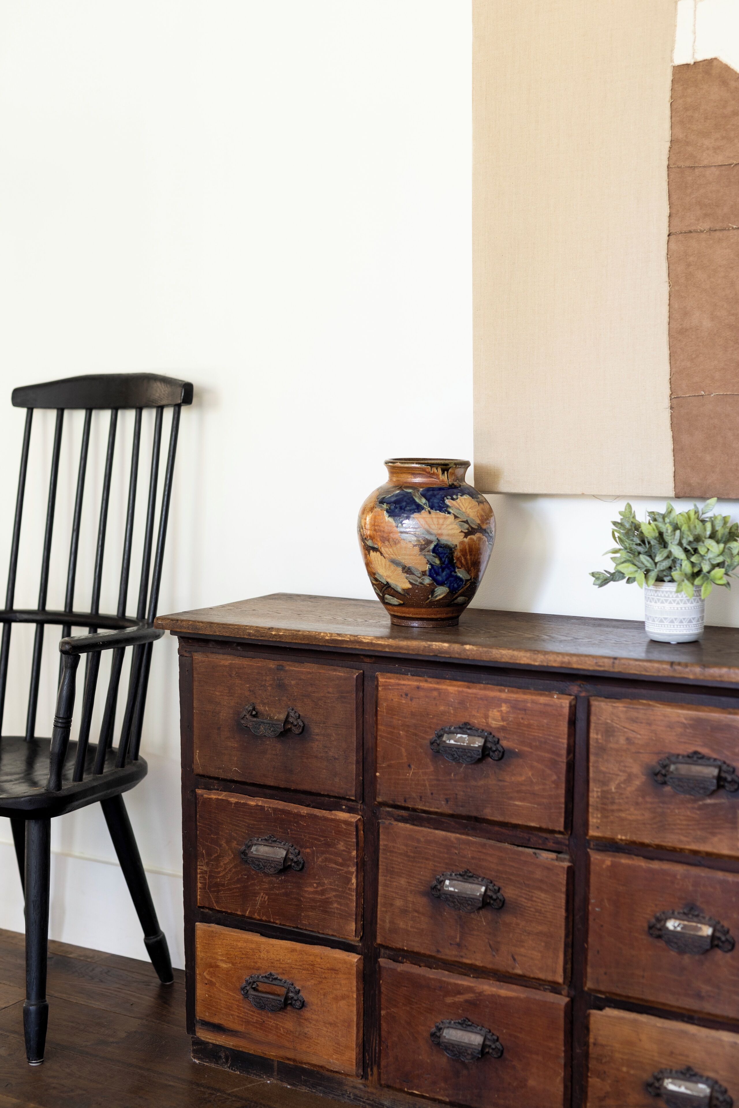 Un aparador de madera con varios cajones y un jarrón decorativo encima.