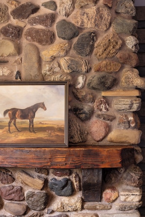 A stone wall with a framed painting of a horse.