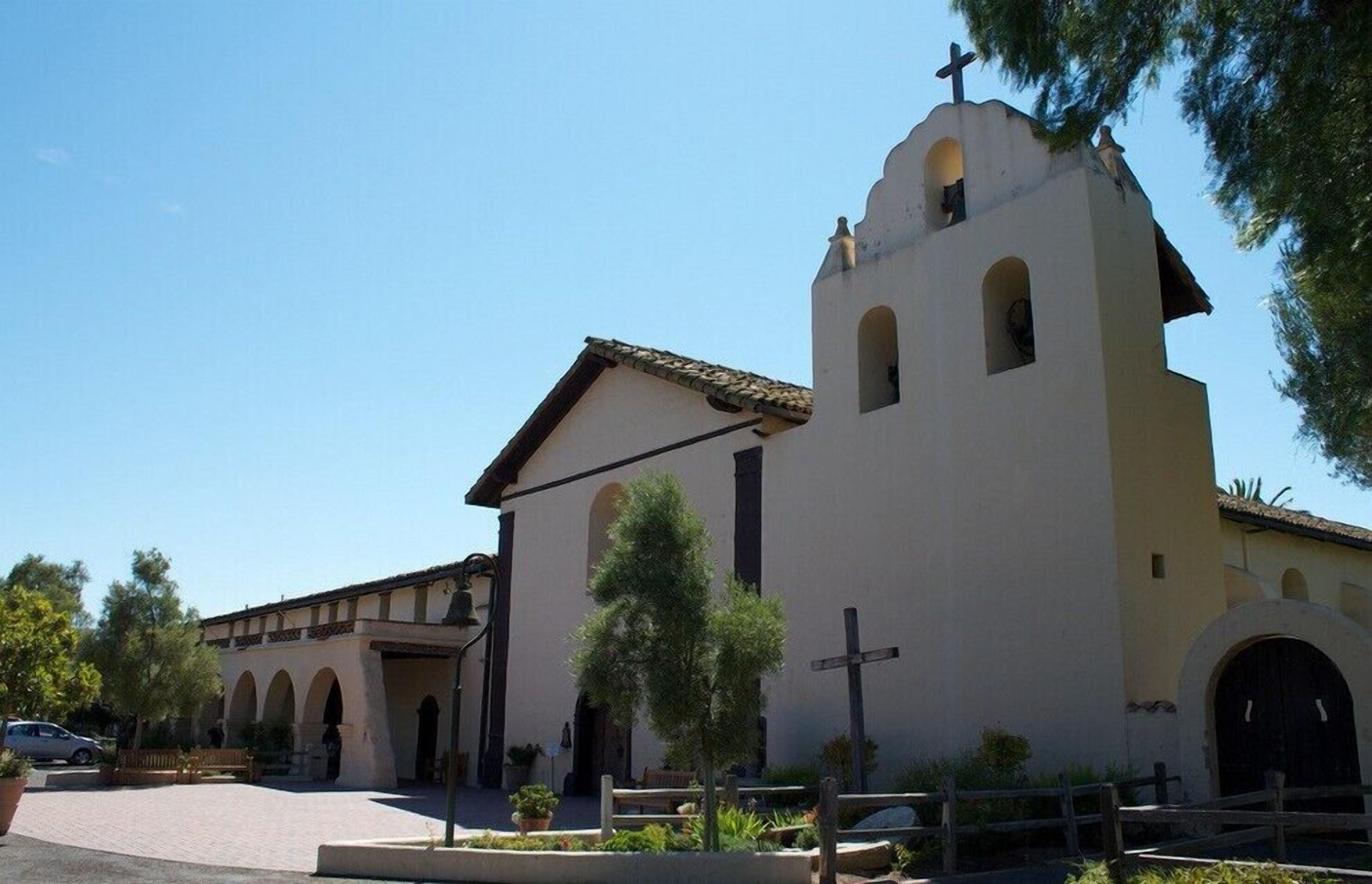 A church with a bell tower, arched windows, and a cross in front.