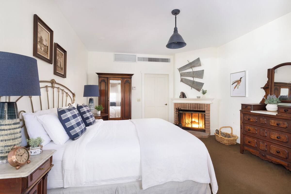 Un dormitorio con cama, cómoda y chimenea.
