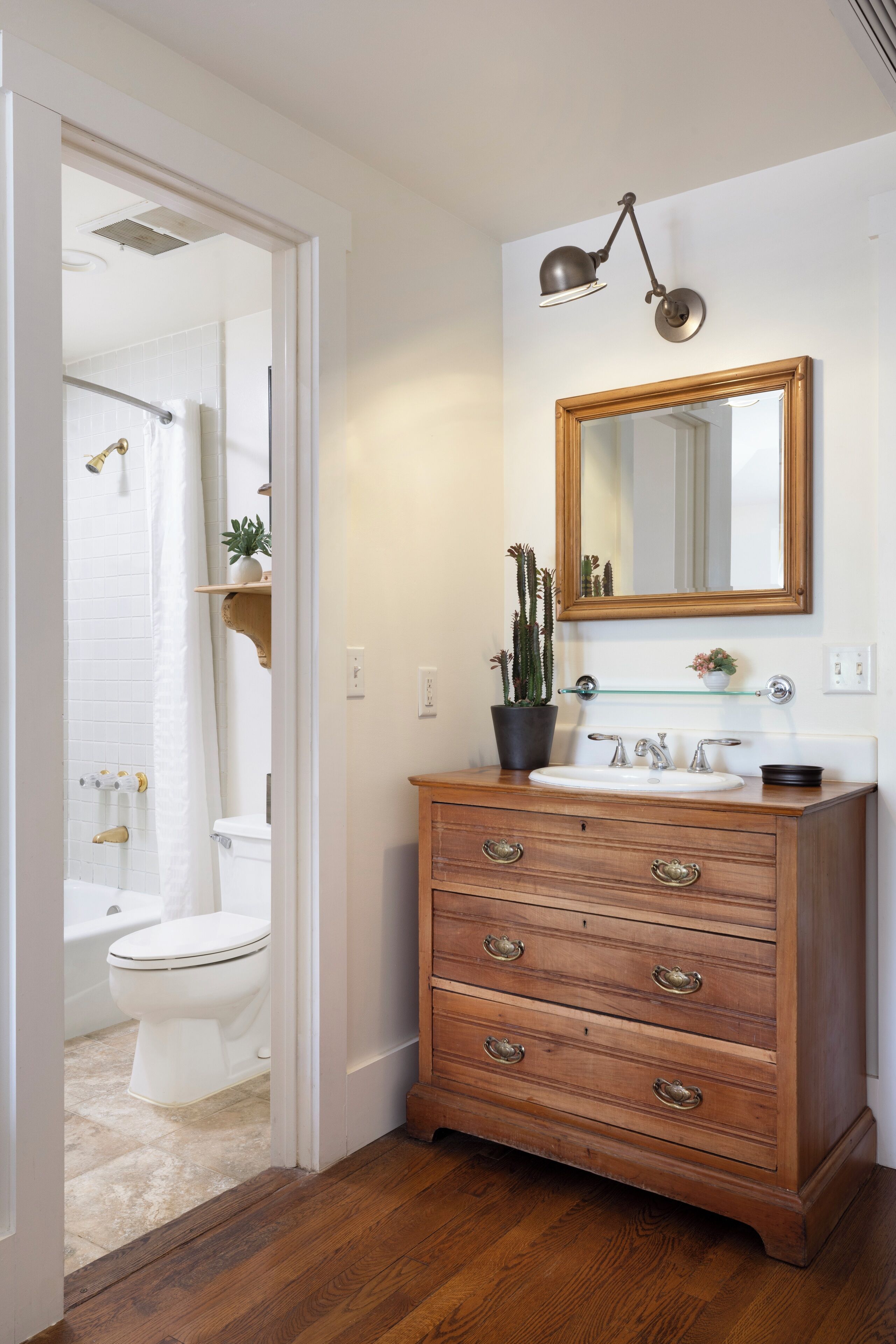 A bathroom with a wooden vanity, a mirror, and a shower area.