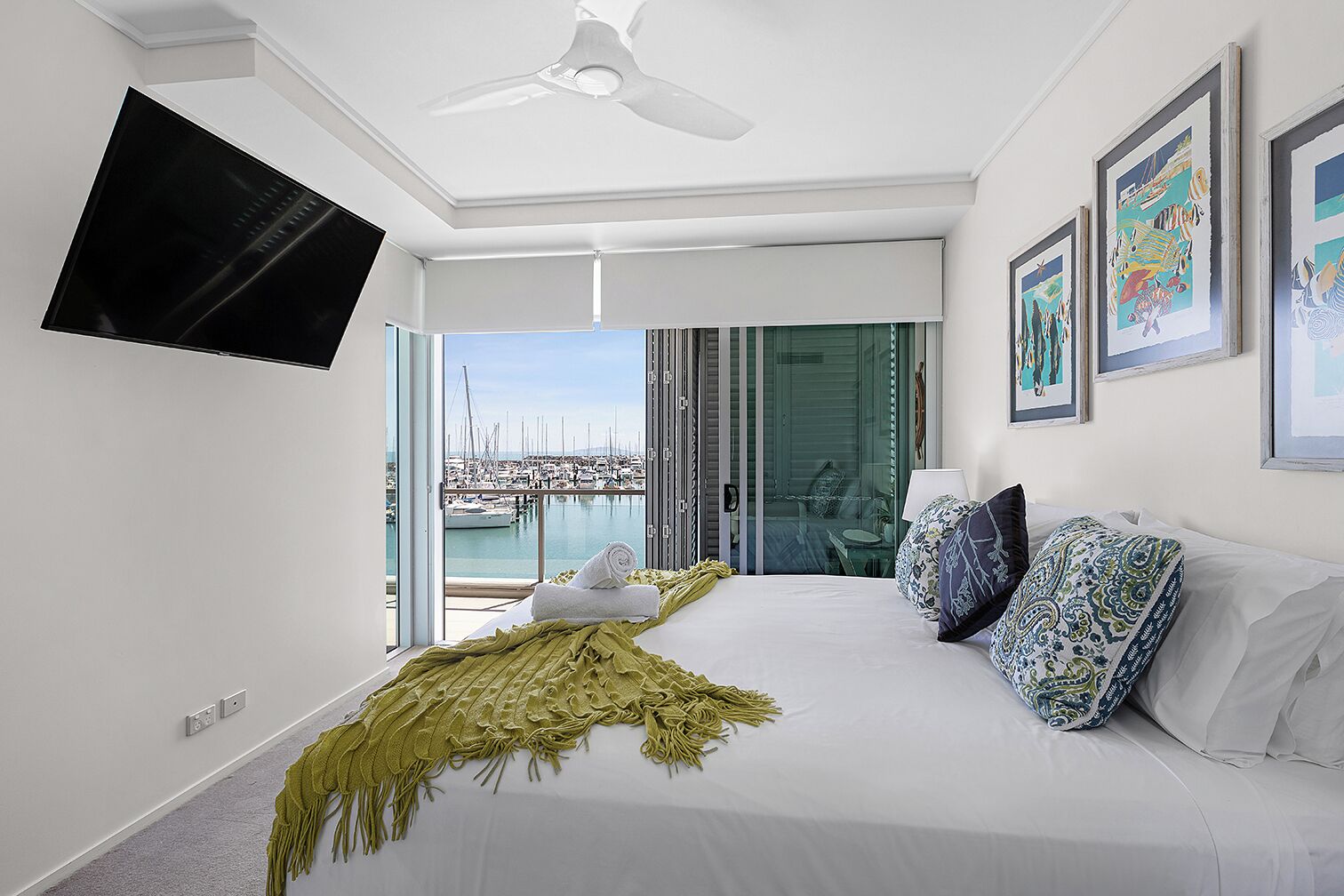 Un dormitorio moderno con una cama grande, un televisor de pantalla plana y vista a un puerto deportivo.