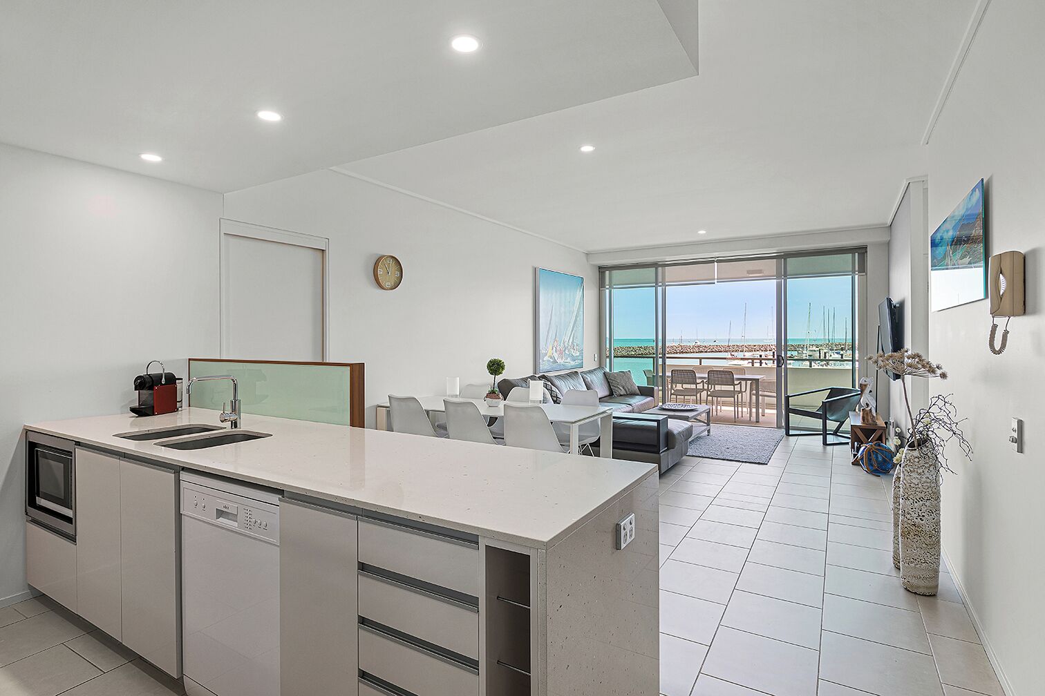 A modern kitchen with a central island, a dining area with a view, and a living space with a balcony.