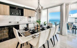 A modern kitchen with a dining area, large windows, and a view of the sea. - Cilento Mooloolaba (Mooloolaba)