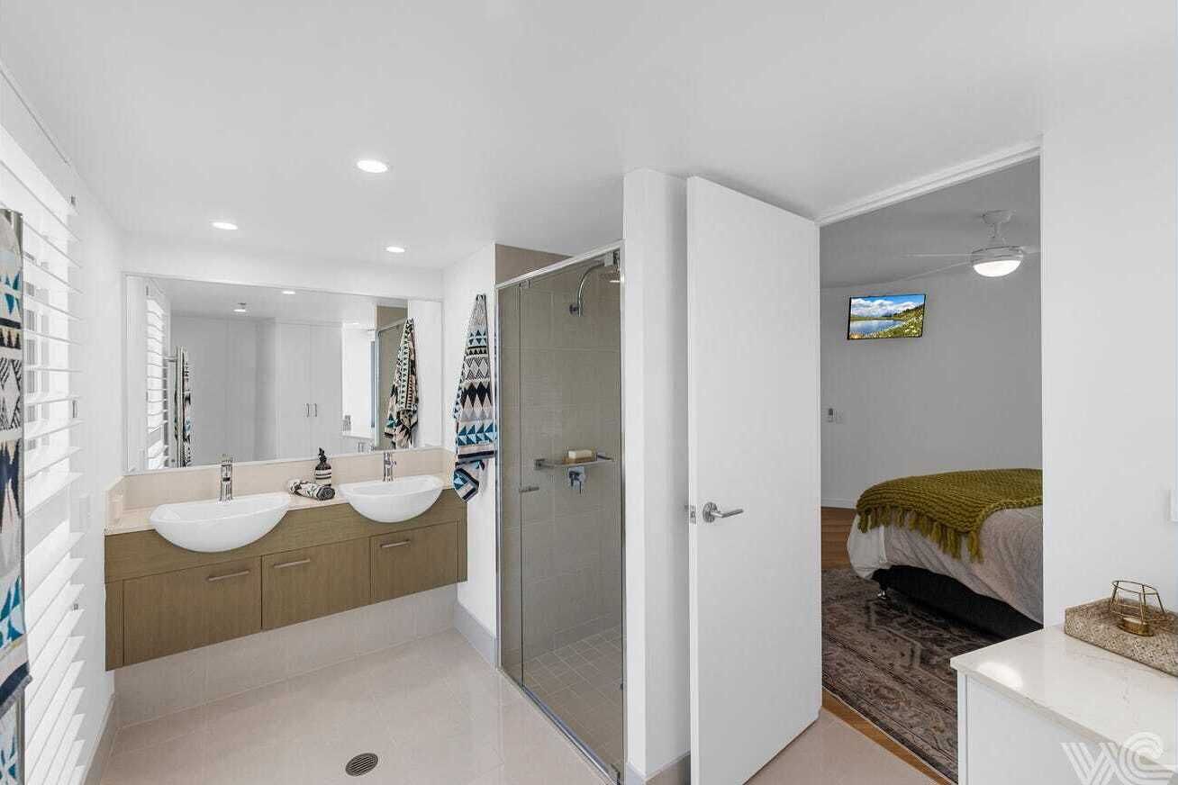 Un baño moderno con dos lavamanos, cabina de ducha de vidrio y un espejo grande.