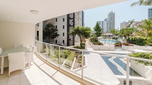 A balcony with a dining area, a pool, and a view of surrounding buildings. - Trilogy Surfers Paradise (Surfers Paradise)