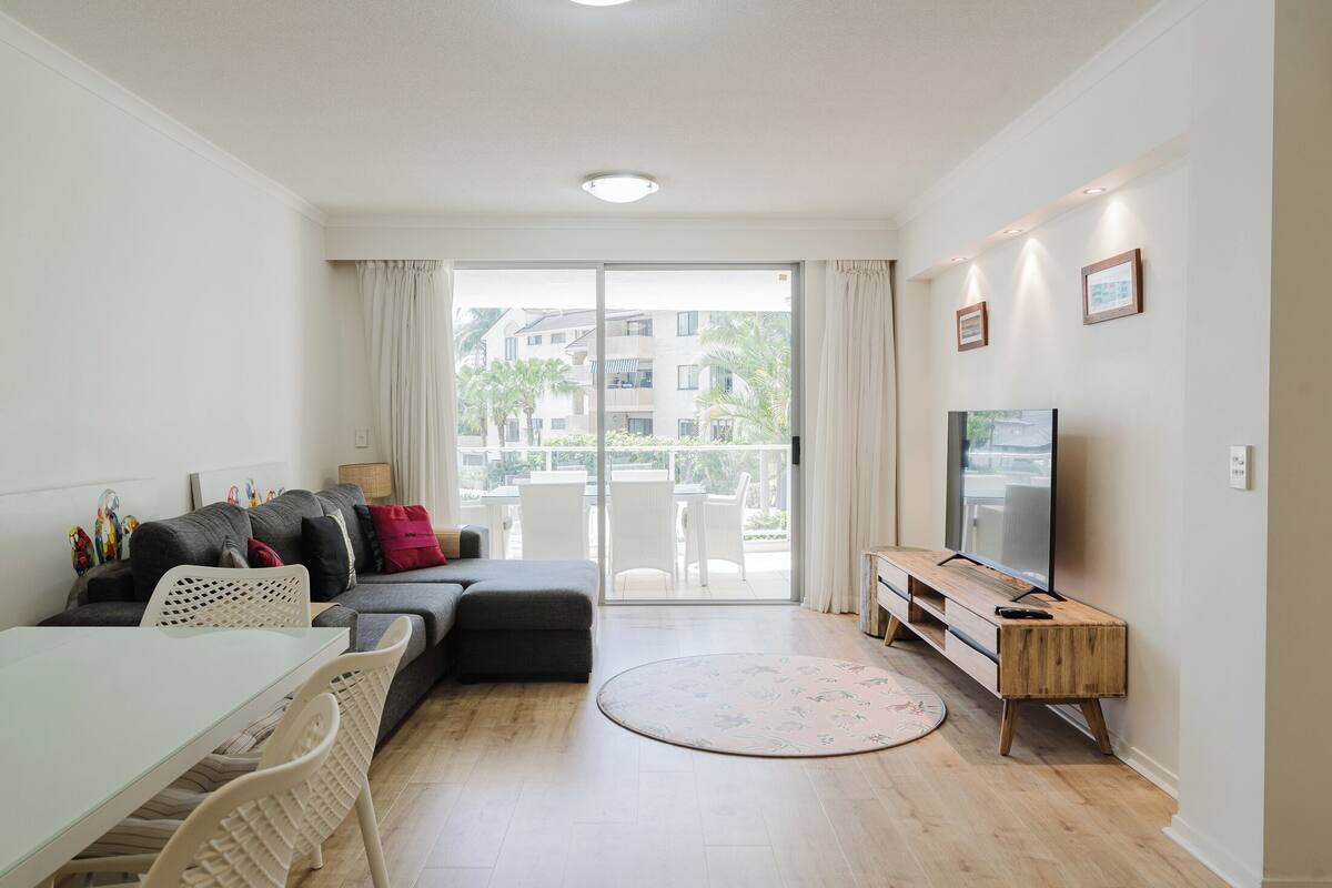 A modern living room with a sofa, a dining table, and a TV.