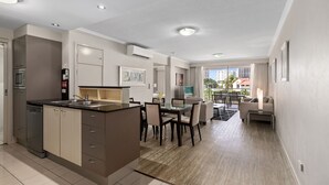 A modern kitchen with a central island, dining area with chairs, and a sofa. - Trilogy Surfers Paradise (Surfers Paradise)