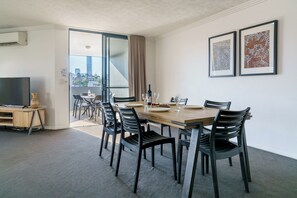A hotel room with a dining area, a television, and artwork on the wall. - Gabba Central Apartments (Woolloongabba)