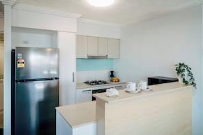 Una cocina moderna con un refrigerador de acero inoxidable, una estufa a gas y alacenas blancas.
