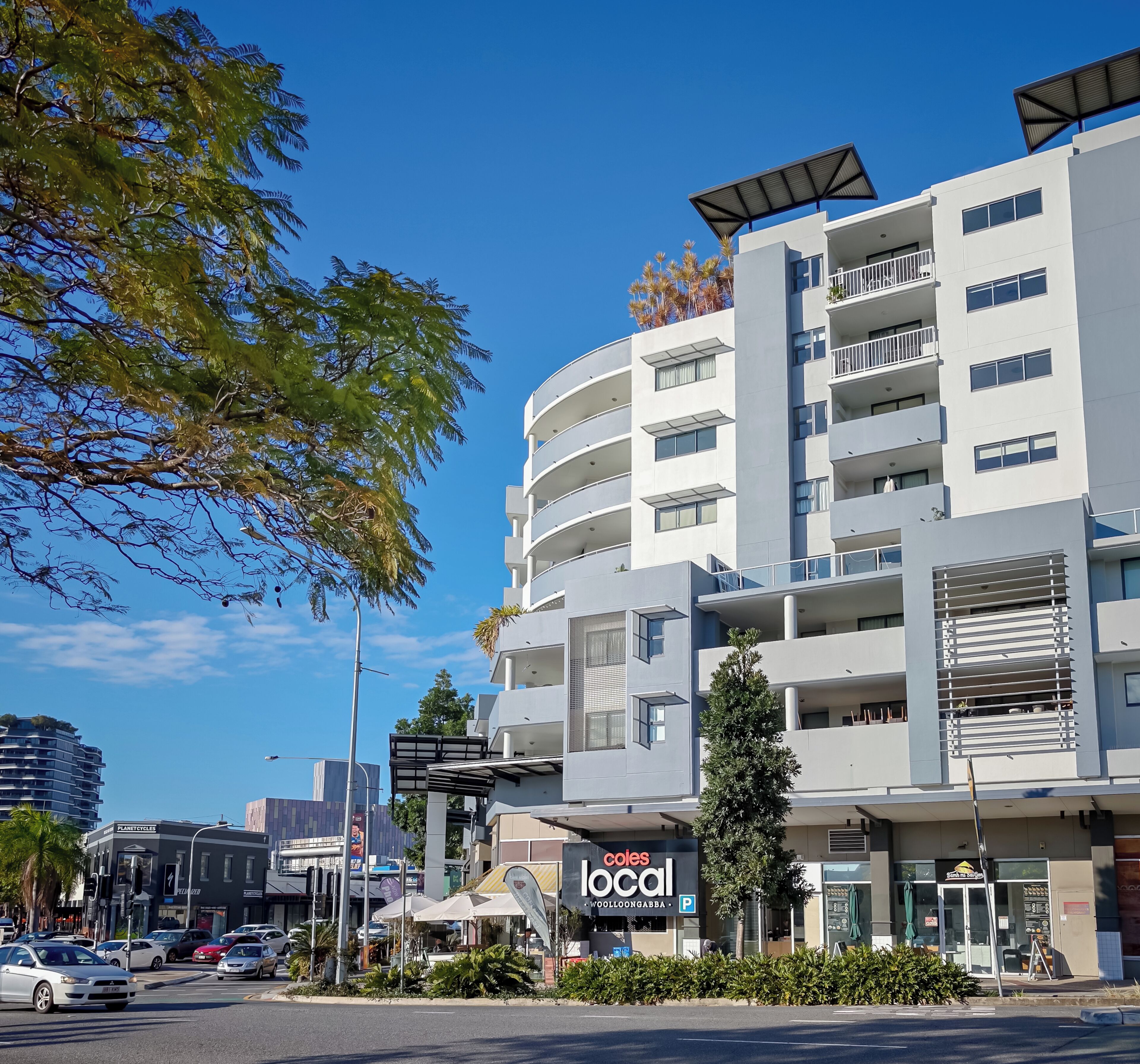 A multi-story building with a commercial ground floor, including a local store and outdoor seating.