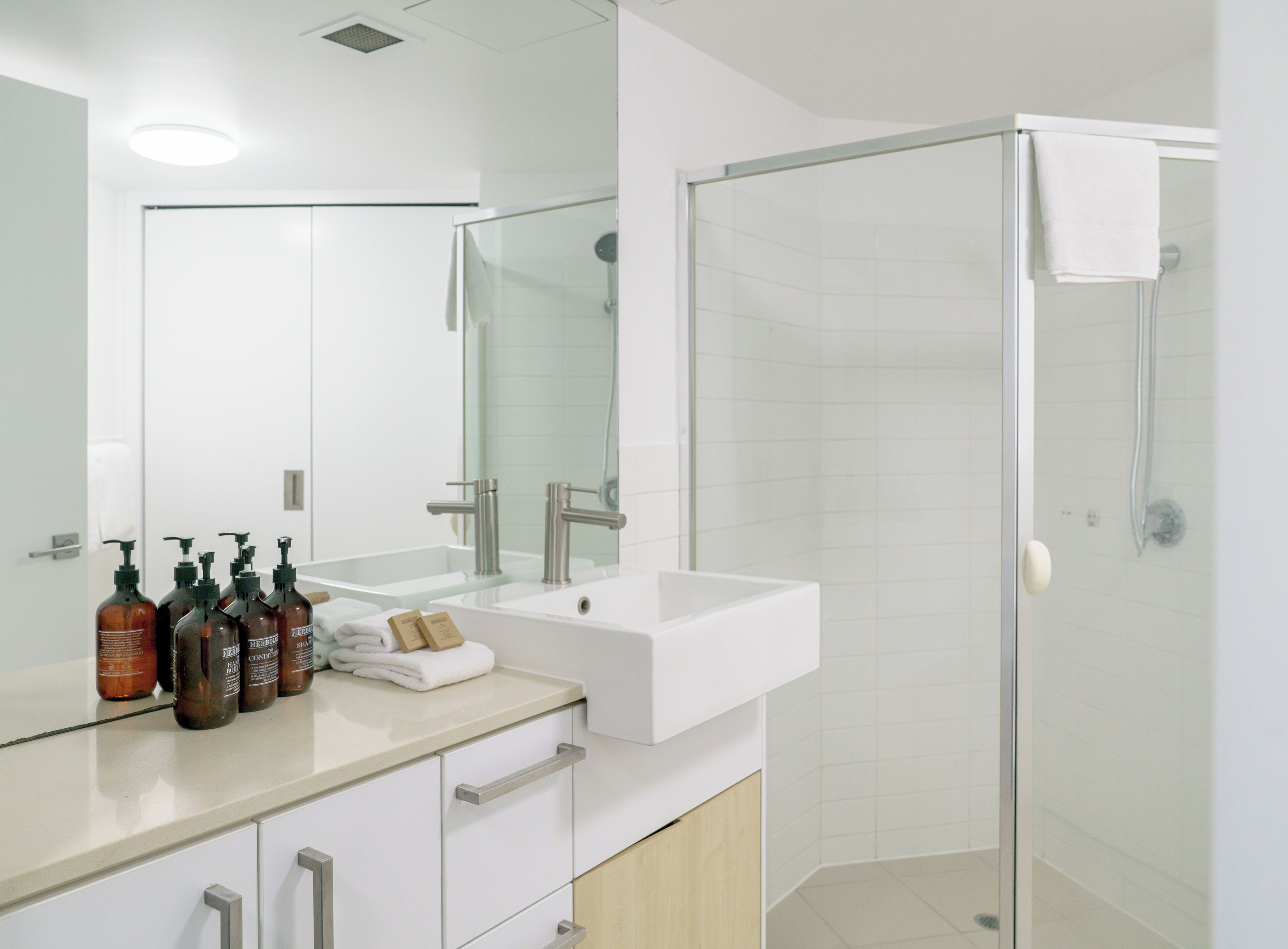 Une salle de bain moderne avec une douche à parois de verre, un lavabo blanc et un miroir au-dessus.
