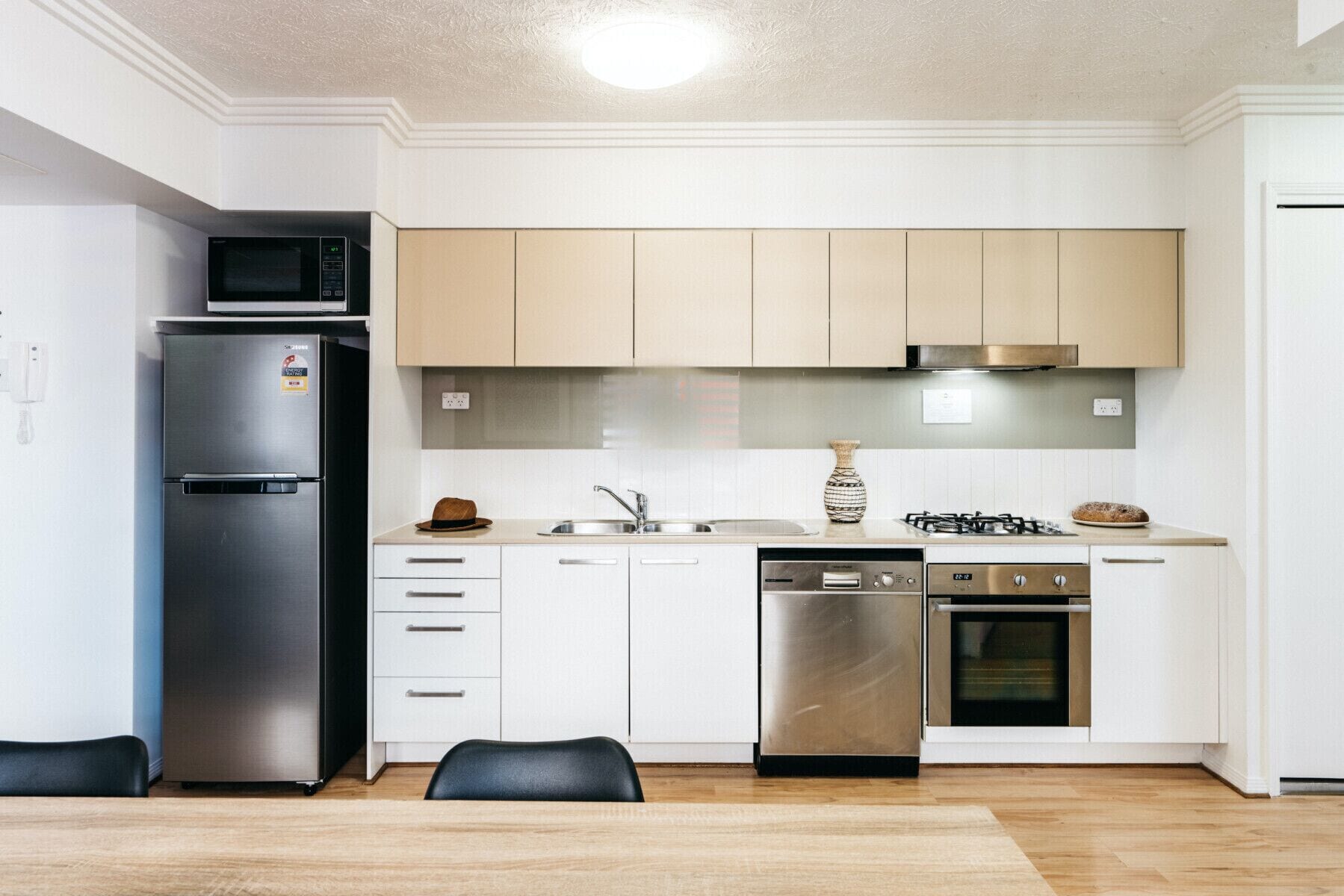A modern kitchen with a stainless steel refrigerator, a dishwasher, an oven, and a gas stove.