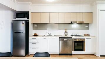 A modern kitchen with a stainless steel refrigerator, a dishwasher, an oven, and a gas stove.
