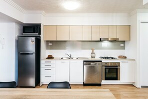 A modern kitchen with a stainless steel refrigerator, a dishwasher, an oven, and a gas stove.