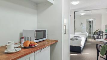 A kitchenette with a microwave, a coffee maker, and croissants on the counter.