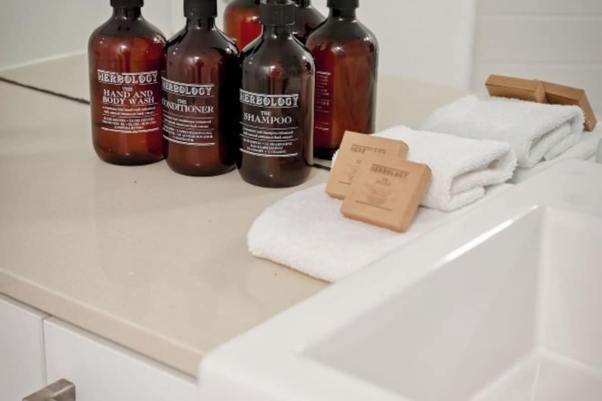 A bathroom counter with bottles of shampoo and conditioner, a towel, and a soap bar.