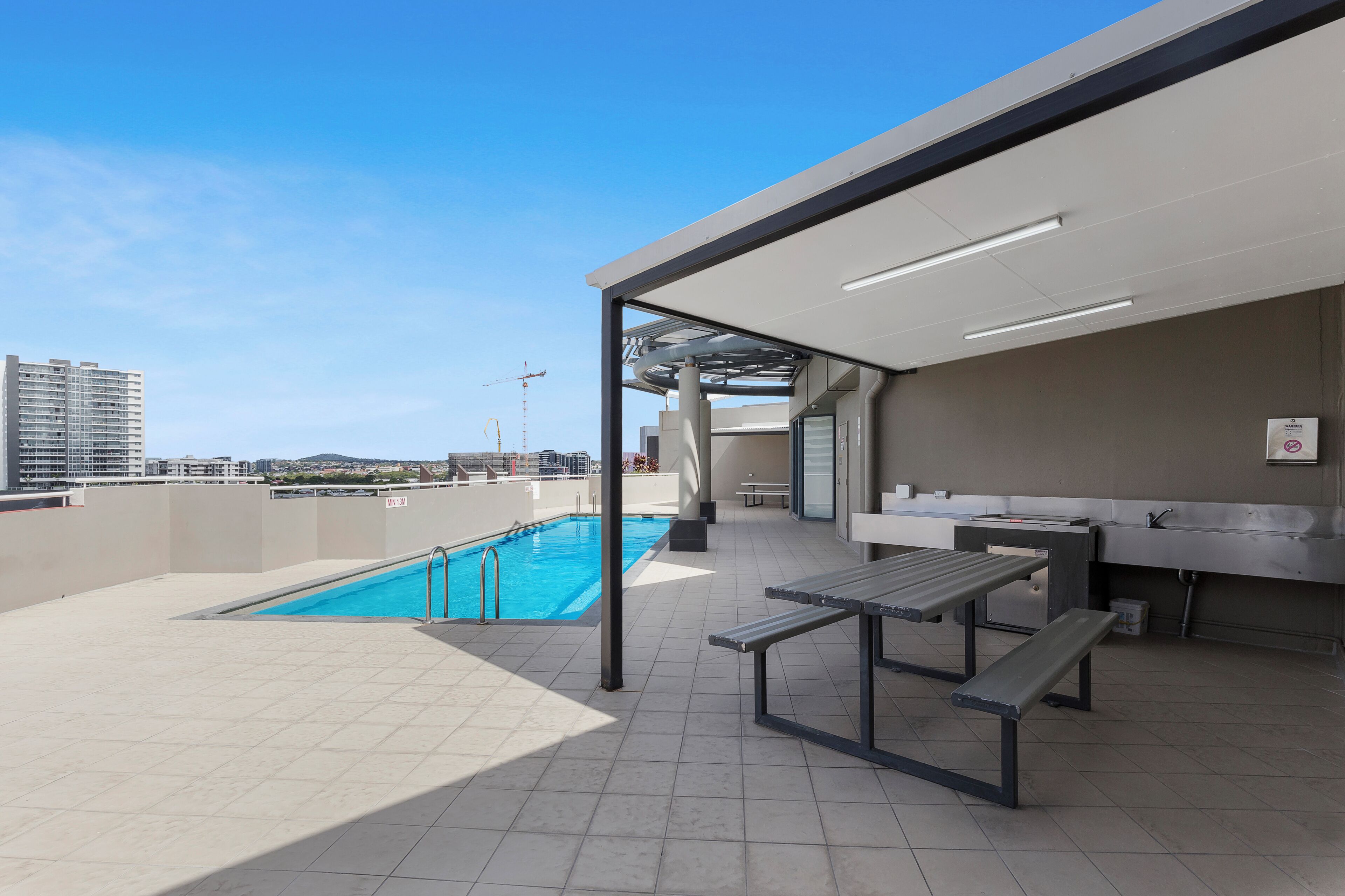 A rooftop pool area with a pool, benches, and a view of the cityscape.