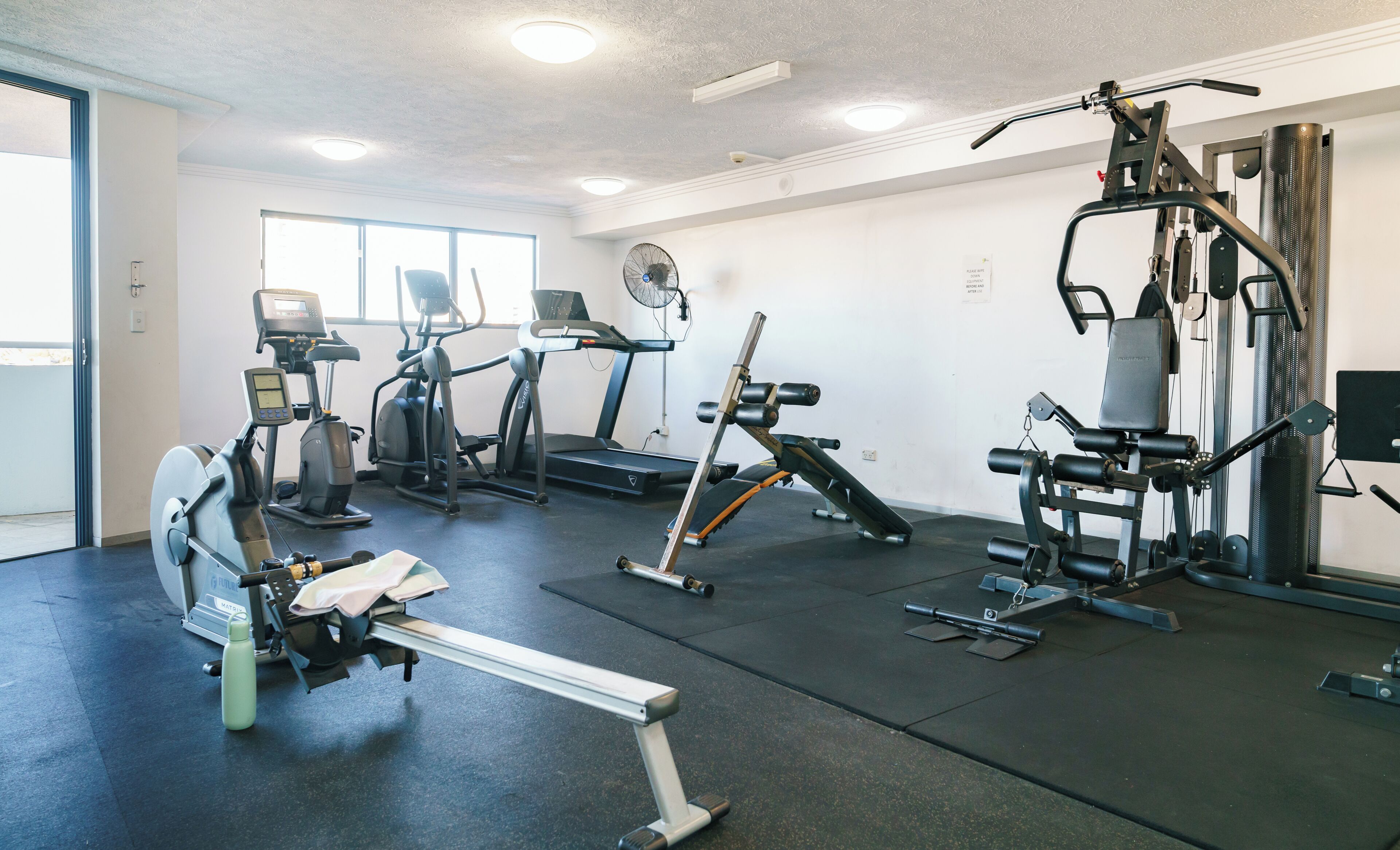 A gym with treadmills, elliptical machines, a rowing machine, and weightlifting equipment.
