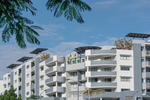 Un hôtel à plusieurs étages doté de balcons, de panneaux solaires et offrant une vue sur un ciel dégagé.