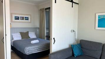 Un dormitorio con cama, sofá gris y puerta corredera.