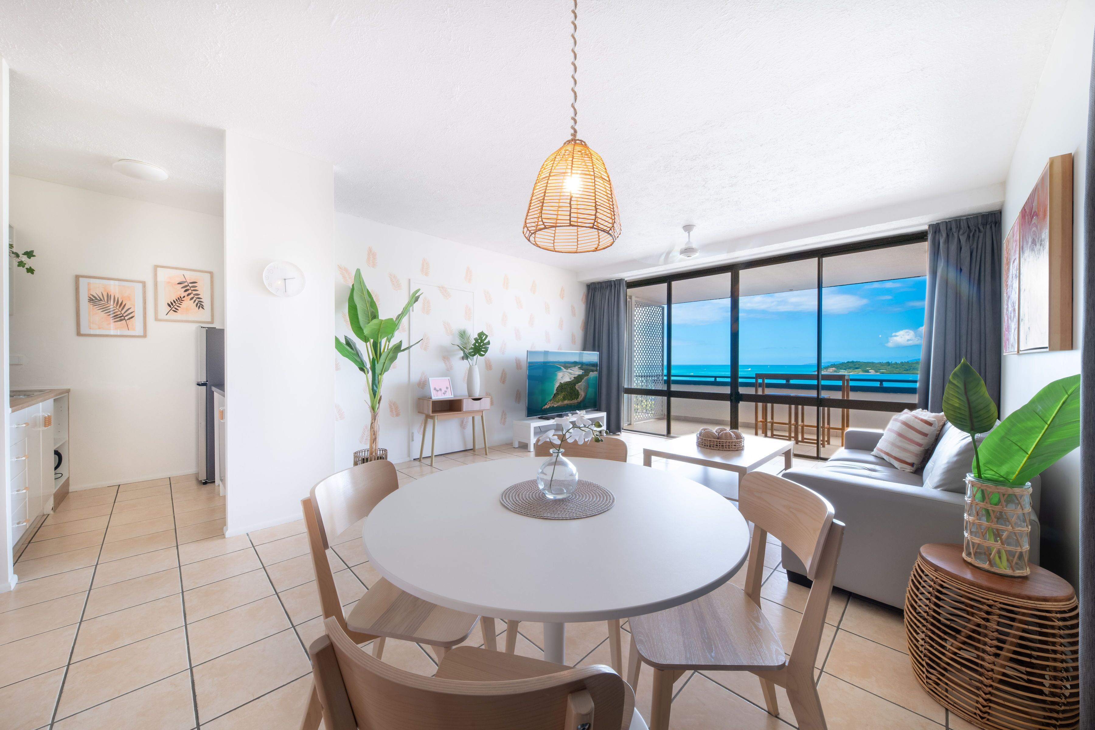 A modern living room with a dining area, large windows with a view, and a cozy seating arrangement.