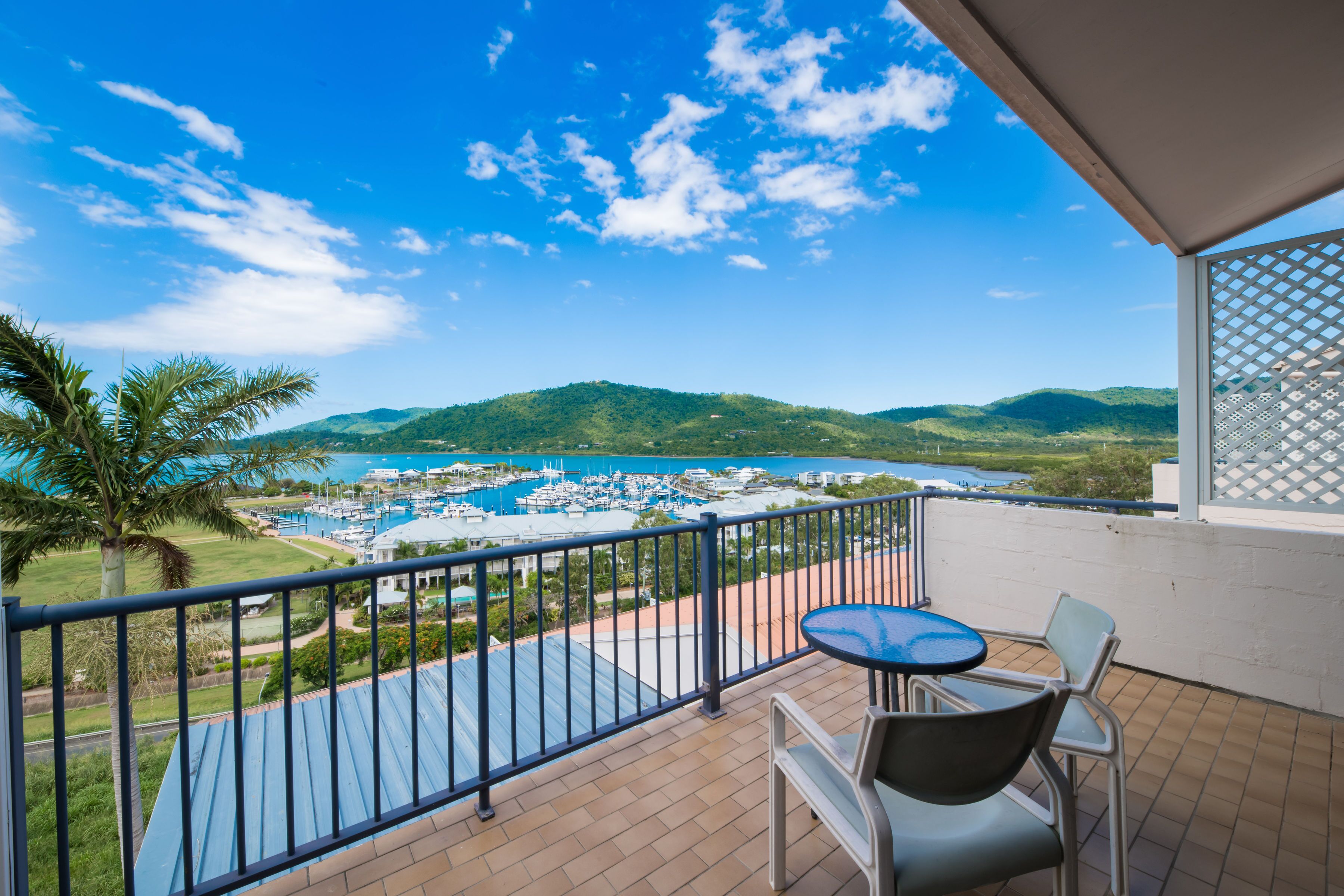 A balcony with a view of a marina, chairs, and a table.