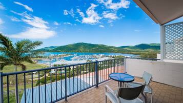 A balcony with a view of a marina, chairs, and a table.