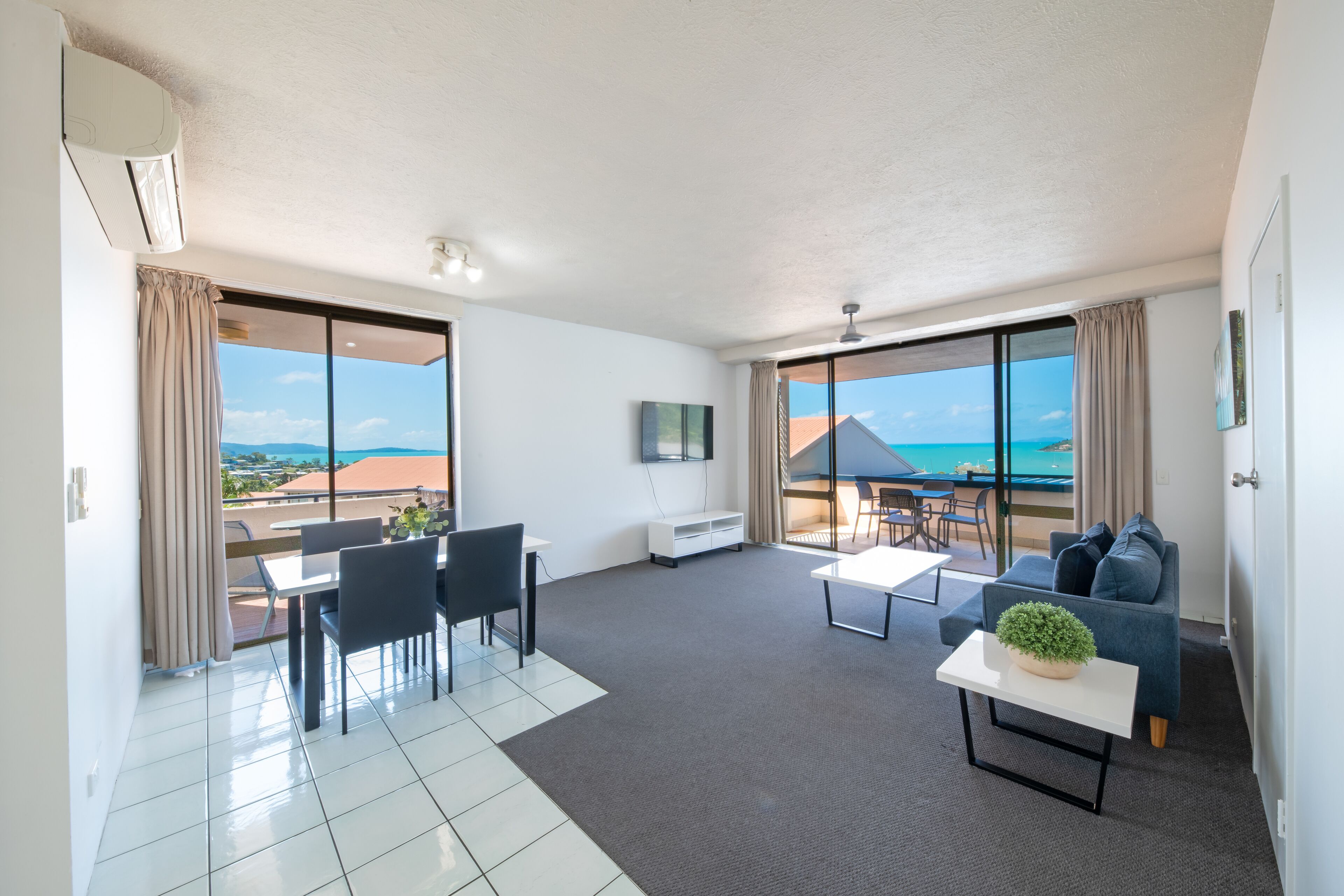 Una sala de estar moderna con balcón, comedor y sofá.
